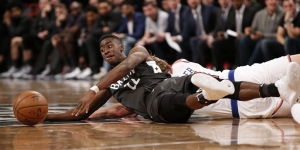 Caris LeVert scrambling on floor to grab ball from Enes Kanter (NY Knicks forward) to keep ball in play.