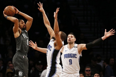 Brooklyn Nets guard, Spencer Dinwiddie, attempting to pass the basketball around Orlando Magic players Isaiah Briscoe (in center) and Nikola Vucevic (on the right)